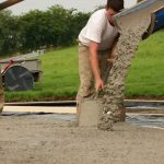 Men pouring concrete for house foundation